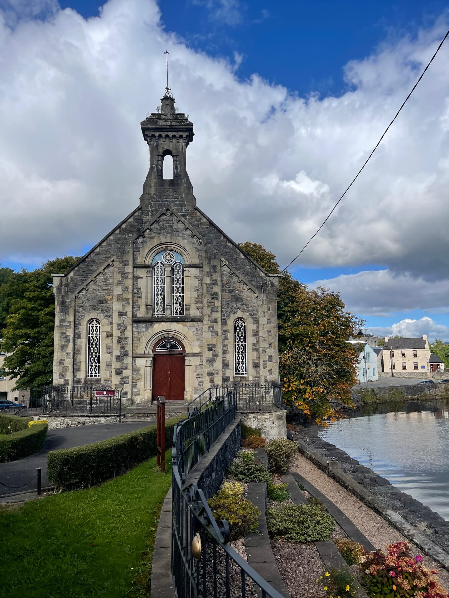 Historic stone church with a bell tower beside a river in Donegal, Ireland